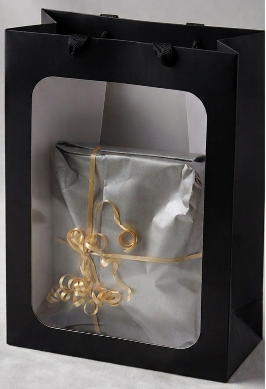 Premium gift wrapping — silver tissue with a gold ribbon bow in a black gift bag