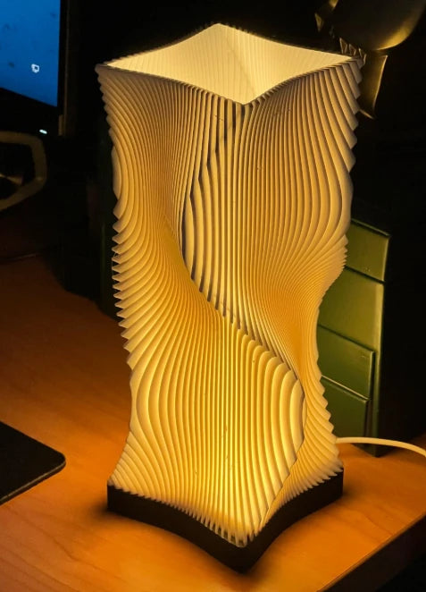 Luméa Helix table lamp with a black base, lit on a desk